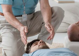 holistic health practitioners hands above clients head
