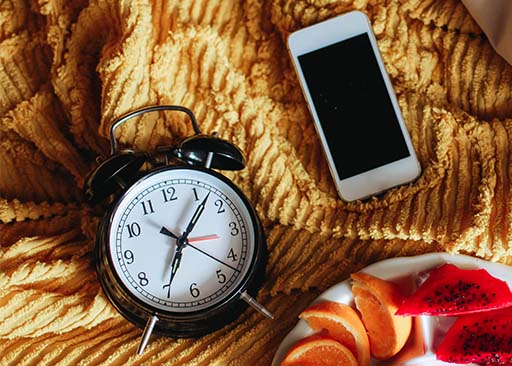 analog clock and smartphone with the best time to sleep and wake up
