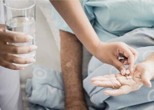 clinical pharmacist placing medication in the hand of patient