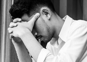 asiatischer mann, der gesicht mit händen bedeckt, die empathie für schmerz brauchen
