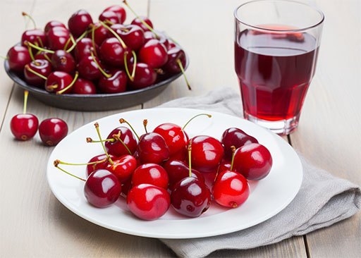 plate of cherries and a glass of tart cherry juice