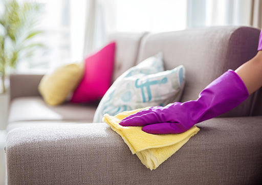 gloved hand dusting furniture with microfiber cloth