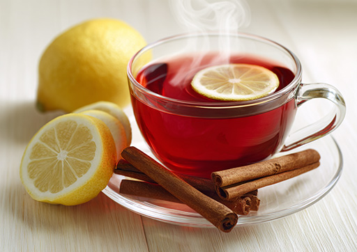 sliced lemon and cinnamon sticks next to roselle tea