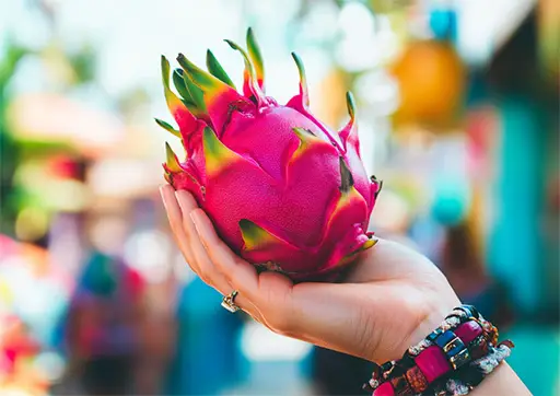 persons hand holding a whole dragon fruit