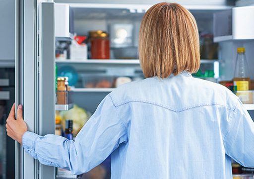 lady looking in fridge with hunger pains after eating