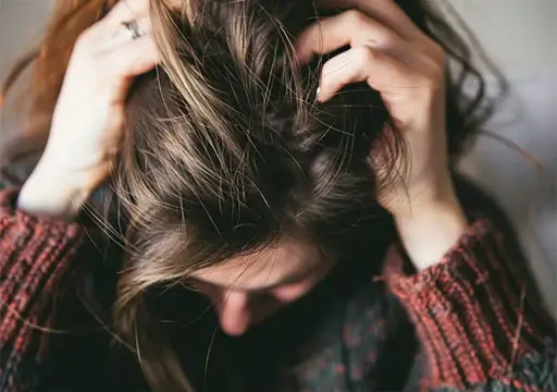 lady with scalp irritation scratching head